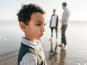 Child in distance as one parent the news of divorce to other spouse